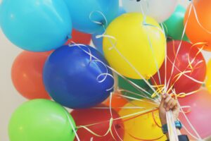 A person holding balloons with birthday party rentals.